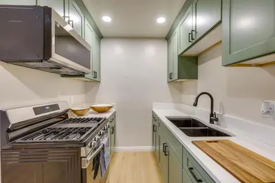 a kitchen with green cabinets and a stove and sink at 1 Mi to LLUMC! Loma Linda Home with Shared Patio in Loma Linda