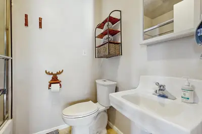 a white bathroom with a toilet and a sink at Lakeview Cabin in Crestline