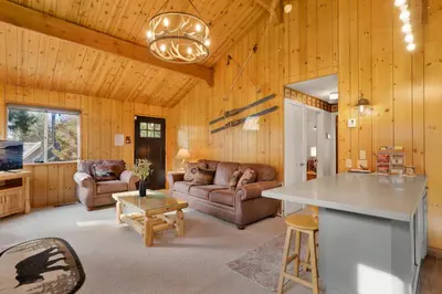 a kitchen and living room with wooden walls at Sweet Dream Cabin on Dream Street | Walk to Alpine Slide, Dining, & Big Bear Fun in Big Bear Lake