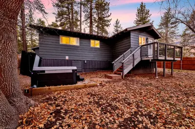 a black house with a staircase in front of it at The Highland Getaway at Big Bear Village | Downtown Modern Retreat Cottage in Big Bear Lake