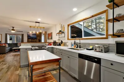 a kitchen with white cabinets and a large window at The Highland Getaway at Big Bear Village | Downtown Modern Retreat Cottage in Big Bear Lake