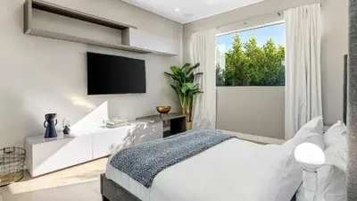 a white bedroom with a tv and a bed at Private LA Retreat w Pool Hot Tub Fire Pit Near Melrose Ave The Martel House by AvantStay in Los Angeles
