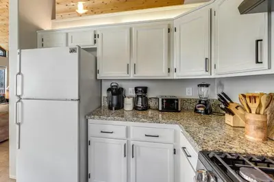 a kitchen with white cabinets and a white refrigerator at 2 Decks! Pet-Friendly Lake Arrowhead Cabin in Lake Arrowhead