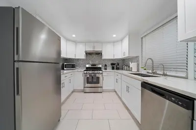 a kitchen with white cabinets and a stainless steel refrigerator at Marbella Lane - Serene & Spacious 3BR Haven in West Covina