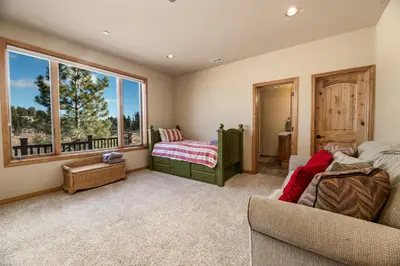a living room with a bed and a window at Boulder Cove։ Lakefront Estate in Big Bear Lake