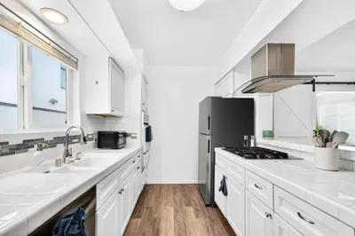 a kitchen with white counters and a sink and a refrigerator at Prime Manhattan Beach 2BR Walk to Beach with Parking in Manhattan Beach
