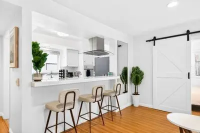 a white kitchen with bar stools and a counter at Prime Manhattan Beach 2BR Walk to Beach with Parking in Manhattan Beach