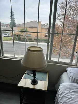 a lamp on a table in front of a window at Big bedroom shared bathroom in Fontana