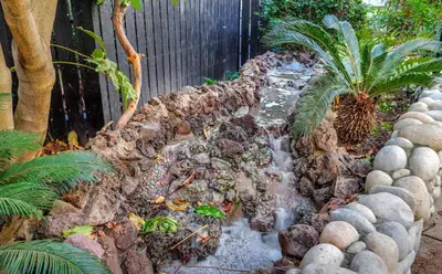 a waterfall in a garden with rocks and plants at A Tranquil Retreat in Tarzana CA in Tarzana