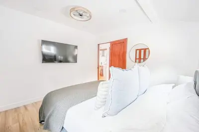 a bedroom with a white bed with a clock on the wall at 2 Units Oasis Villa w terrace&roofdeck 12 pax in Los Angeles
