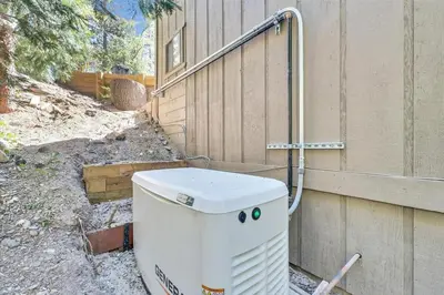 a white water heater sitting next to a fence at Arrowbear Retreat - EV Charging, Generator, Arcade in Arrowbear Lake