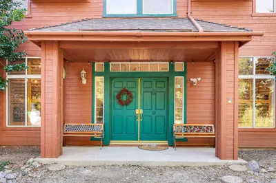 a green front door of a house with two benches at Games Galore! Pine Mountain Club Retreat Near Town in Pine Mountain Club