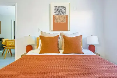 a bedroom with a bed with orange sheets and pillows at Relaxing 4BR LA Home Private Pool & Fire Pit in Los Angeles