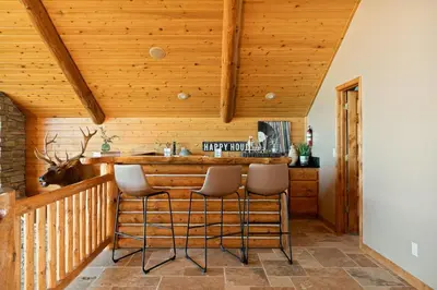 a bar in a log cabin with stools at Hawk Ridge Chalet In Big Bear Lake in Big Bear Lake