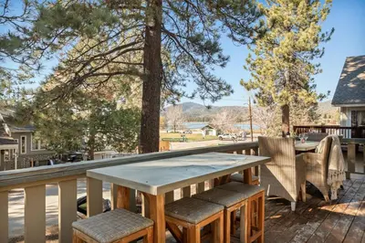 a wooden table and chairs on a deck with trees at Live Love Lake in Big Bear Lake