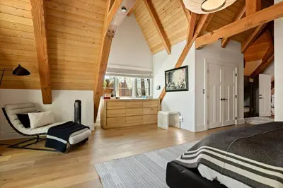 a bedroom with wooden ceilings and a bed and a chair at Seuss by the Shore in Big Bear Lake