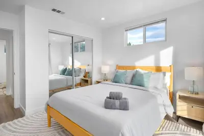 a white bedroom with a large bed and a mirror at Luxe 3BR South Bay - Comfort and Close to Beach in Harbor City