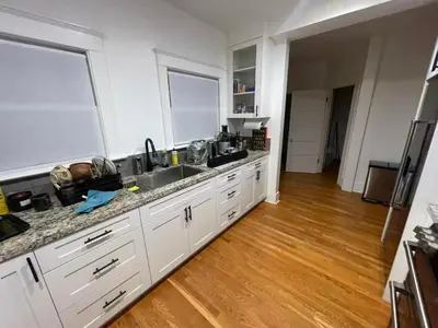 a kitchen with white cabinets and a wooden floor at Hollywood Heritage Villa in Los Angeles