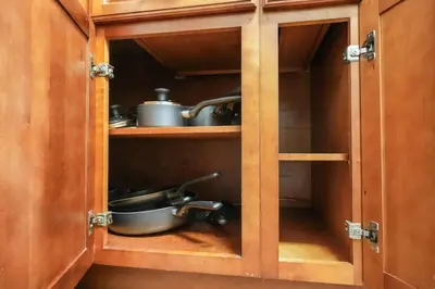 a cabinet with some pots and pans in it at Steps to Beach - Beach Essentials Provided! in Long Beach