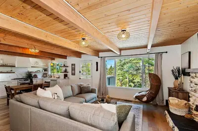 a living room with a couch and a kitchen at Yama Cabin - 5 min walk to the village, EV plug, hot tub, kid & pet friendly in Lake Arrowhead