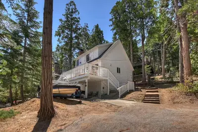 a large white house with a boat in front of it at Yama Cabin - 5 min walk to the village, EV plug, hot tub, kid & pet friendly in Lake Arrowhead