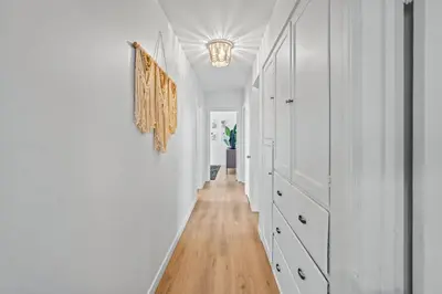 a hallway with white walls and wood floors and a chandelier at Belmont Shore Getaway with Hot Tub and Firepit in Long Beach