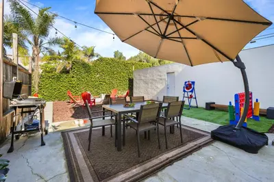 a patio with a table and chairs and an umbrella at Belmont Shore Getaway with Hot Tub and Firepit in Long Beach