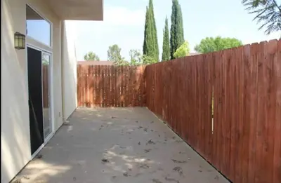 a backyard with a wooden fence and a sidewalk at Woodland Oasis 2BR With FREE PARKING in Canoga Park