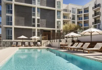 a swimming pool with chairs and umbrellas next to a building at Luxe on Hollywood Blvd 2BR with FREE PARKING in Los Angeles