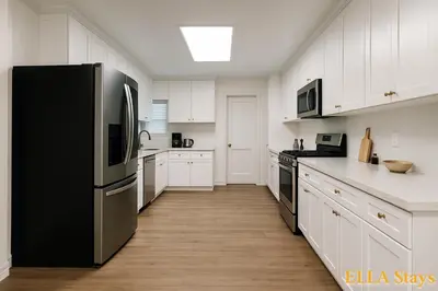 a kitchen with a black refrigerator and white cabinets at Rowland Heights Cozy & Quiet Home in Rowland Heights