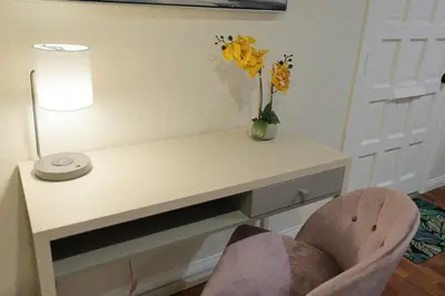 a white desk with a vase of flowers and a chair at Modern Oasis Studio - near LAX, SoFi, USC, DTLA in Los Angeles