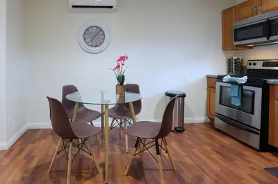 a kitchen with a table with chairs and a clock on the wall at Modern Oasis Studio - near LAX, SoFi, USC, DTLA in Los Angeles