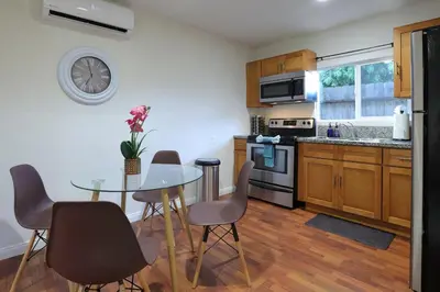 a kitchen with a table and chairs and a clock on the wall at Modern Oasis Studio - near LAX, SoFi, USC, DTLA in Los Angeles