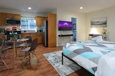 a bedroom with a bed and a kitchen with a table at Modern Oasis Studio - near LAX, SoFi, USC, DTLA in Los Angeles