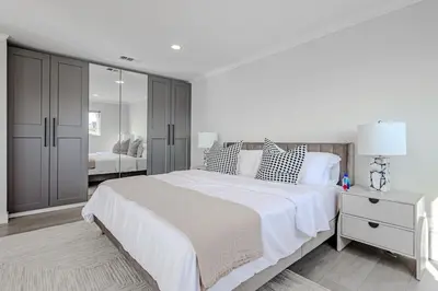 a white bedroom with a large bed and a mirror at Modern 5 Bed with Guest House & Pool West Hollywood in Los Angeles