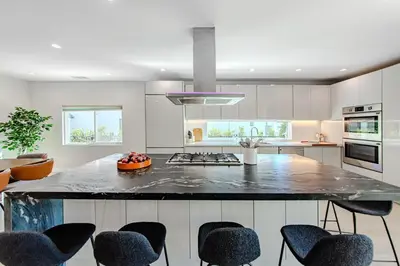 a kitchen with a large counter with chairs around it at Modern 5 Bed with Guest House & Pool West Hollywood in Los Angeles