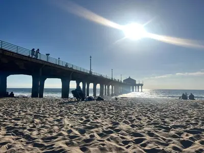 a beach with a pier with the sun in the sky at Ocean View Penthouse 2 Bdrm 2 Bath w garage 2 Blocks to sand in Manhattan Beach