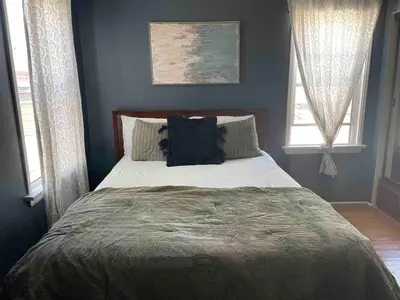 a bed in a bedroom with two windows at 2BR LA Beach City House With Gym & Tesla Charging in Harbor City