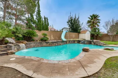 a swimming pool with a slide in a backyard at Pool, Patio and Games! Suburban Home in Palmdale in Palmdale