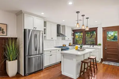 a kitchen with white cabinets and a stainless steel refrigerator at Historical Craftsman with Modern Amenities in Los Angeles