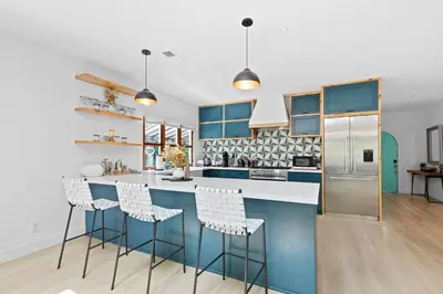 a kitchen with blue cabinets and bar stools at Luxury 4BR Villa with Private Pool in Los Angeles Crescent Heights in Los Angeles