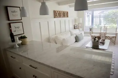 a living room with a white couch and a table at Exquisite Carpinteria Beach Cottage, Steps Away From The Beach in Carpinteria