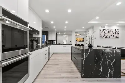 a kitchen with white cabinets and a black counter top at Sleek 7BR Exquisite Estate Resort Pool, Sauna, Spa 6500 SQF in Woodland Hills
