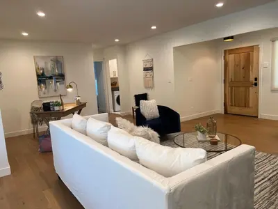 a living room with a white couch and a glass table at Quintessential SoCal indoor outdoor living with POOL in Long Beach