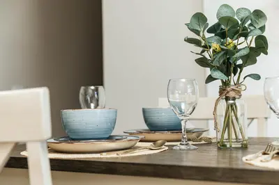 a table with plates and glasses and a vase with flowers at Cozy 2B Apartment in Santa Monica in Los Angeles