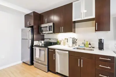 a kitchen with wooden cabinets and stainless steel appliances at Sunny Santa Monica Retreat, Walk to Beach in Santa Monica