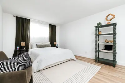 a white bedroom with a bed and a chair at Pacific Aura in Los Angeles