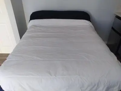 a bed with a white bedspread on top of it at Normandie Vibes Hostel in Los Angeles