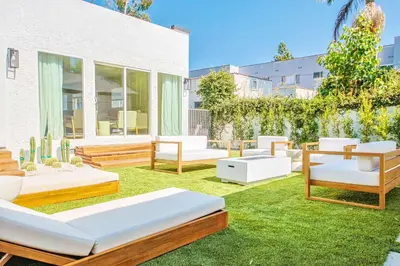 a backyard with several beds and chairs on the grass at Chic 6BR West Hollywood Villa with Jacuzzi in Los Angeles