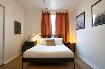 a bedroom with a bed and a window with orange curtains at Curated Central Location LA in Los Angeles